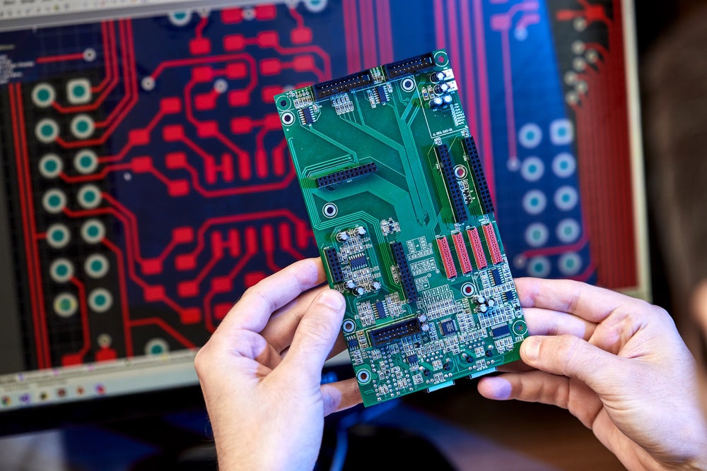 Engineer examining an electronic circuit, performing analysis