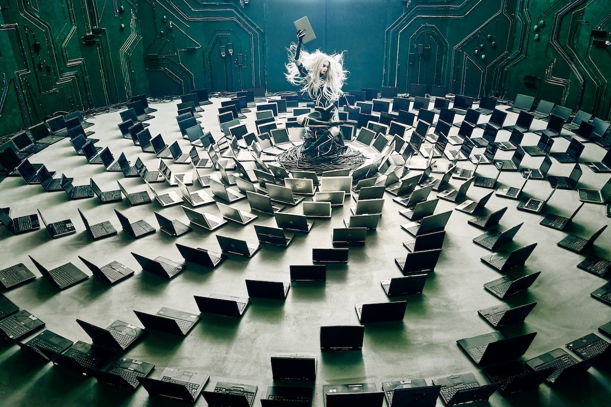 Photo #1 in the series: a cyborg model sits among a vortex of discarded laptops.